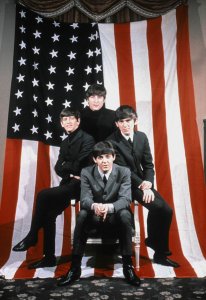 The Beatles pose for a portrait in front of an American Flag, Paris, 1964 January 18