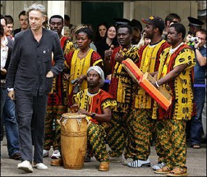 Sir Bob Geldof(L) is welcomed by African musicians upon his arrival at Waverley rail station in Edinburgh, Scotland. Geldof arrived in Scotland with hundreds of supporters of the Make Poverty History campaign